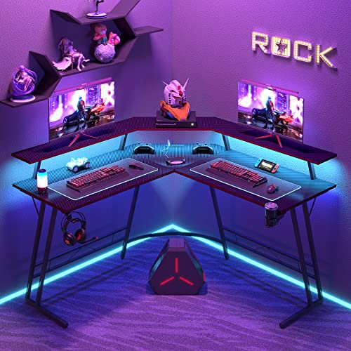 Flamaker Gaming Desk with LED Lights & Power Outlets, L-Shaped Computer Corner Desk with Carbon Fiber Surface & Monitor Stand, Ergonomic Gamer Table with Cup Holder, Headphone Hook, Black