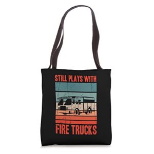 still plays with fire trucks for funny firefighter tote bag