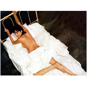 angelina jolie lying on stomach on bed covered white sheets holding bed frame leg bent looking back and up smiling top view 8 x 10 inch photo