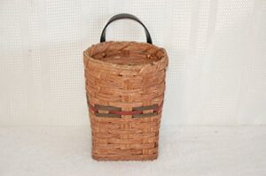 hand woven utensil wall hanging basket. this cute basket is handmade locally here in ohio by the local amish. it is a very handy basket that allows you to store your utensils in a basket on the wall saving space on your counters. measures: 4" x 3" x 8" ta