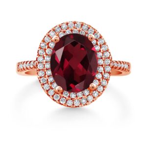 Gem Stone King 18K Rose Gold Plated Silver Red Rhodolite Garnet and Moissanite Halo Engagement Ring For Women (2.43 Cttw, Oval 9X7MM, Gemstone Birthstone, Available In Size 5, 6, 7, 8, 9)